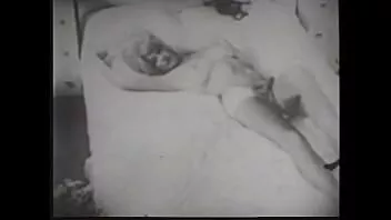 Riproduci Una pornostar tettona in lingerie nera accarezza la sua figa bagnata in un film erotico degli anni '60